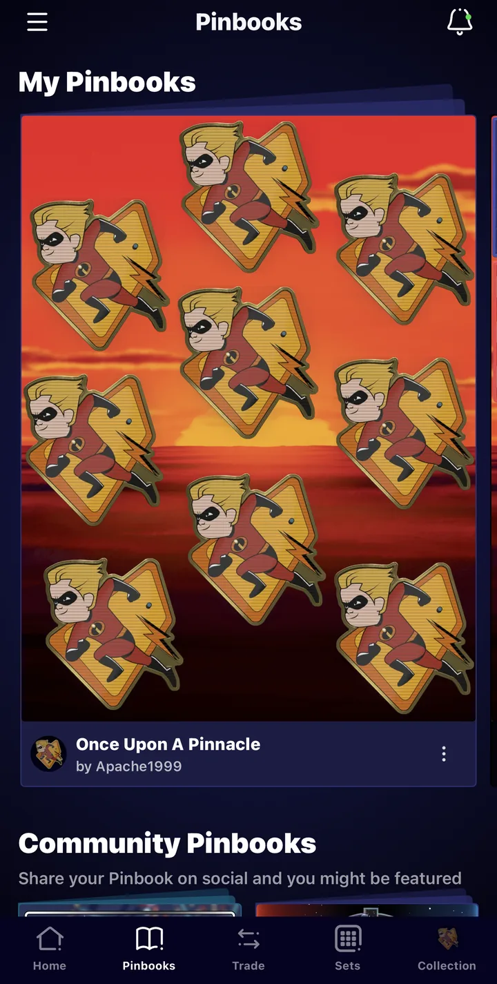 The Pinbooks tab in the Disney Pinnacle app. Under My Pinbooks is the Pinbook Once Upon A Pinnacle by Apache1999, a sunset background filled with Dash pins, and Community Pinbooks starts below it. The bottom bar shows Home, Pinbooks (selected), Trade, Sets and Collection.